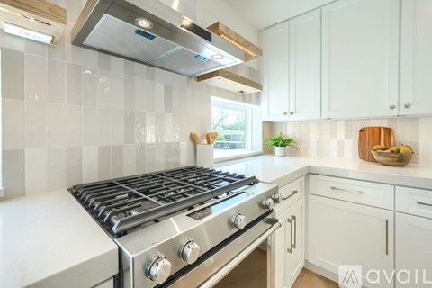 A modern kitchen with a stainless steel gas stove and white cabinets.