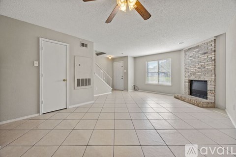A spacious living room with a fireplace and a ceiling fan.
