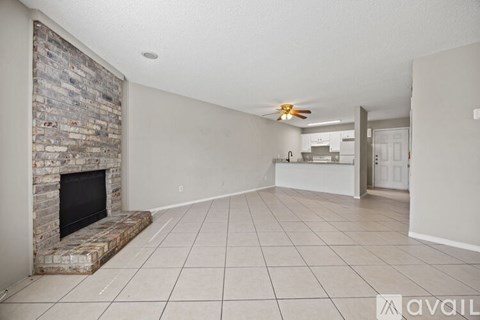 A living room with a stone fireplace and tiled floor.