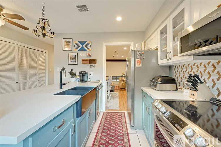 A kitchen with a white counter top and blue cabinets.