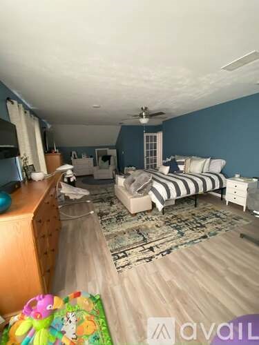 A bedroom with a bed, dresser, and ceiling fan.