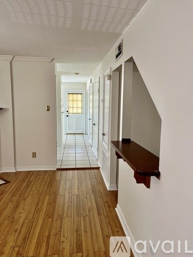 A long hallway with wooden floors and white walls.