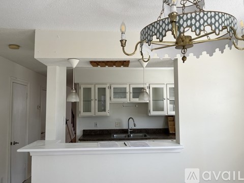 A kitchen with a white countertop and a chandelier hanging from the ceiling.