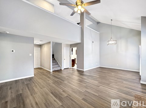A spacious room with a ceiling fan and wooden flooring.