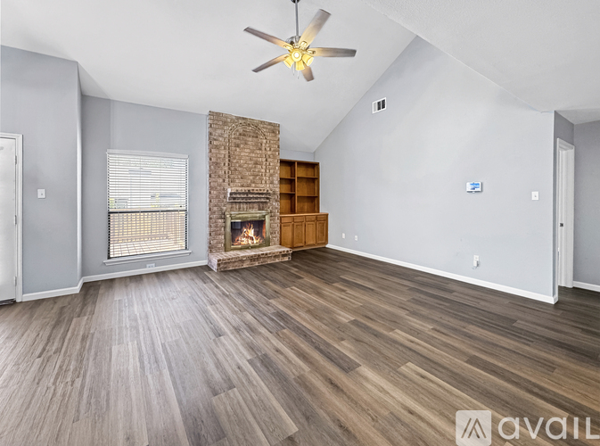 A spacious living room with wood flooring and a fireplace.