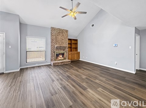 A spacious living room with wood flooring and a fireplace.