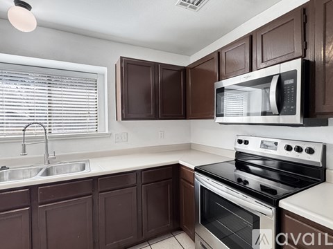 A kitchen with brown cabinets and a white stove top oven.