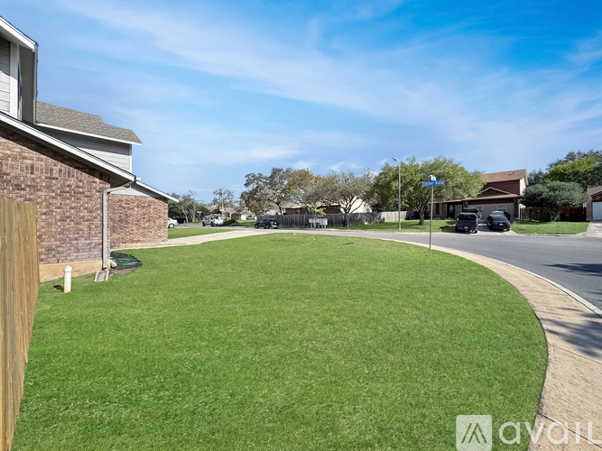 A grassy area in front of a house with a clear blue sky.
