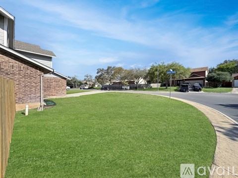 A grassy area in front of a house with a clear blue sky.