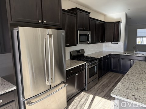 A kitchen with a stainless steel refrigerator and black cabinets.