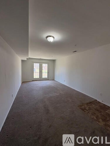 A room with a carpeted floor and a window with blinds.