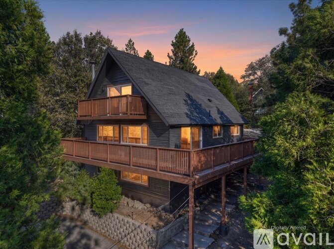 A house with a balcony is surrounded by trees.