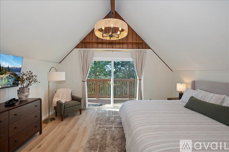 A bedroom with a large bed and a balcony overlooking a deck.