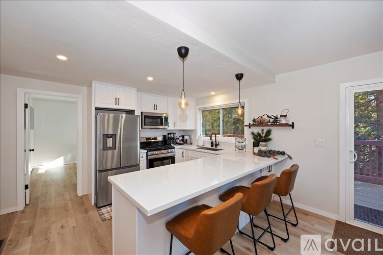 A kitchen with a white island and brown chairs.