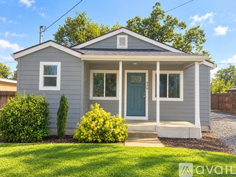 A small house with a grey exterior and a blue door.