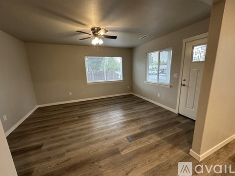 A room with a ceiling fan and wooden flooring.