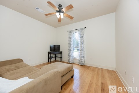 A living room with a brown sofa and a ceiling fan.