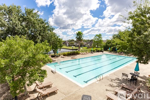 A large swimming pool surrounded by trees and lounge chairs.