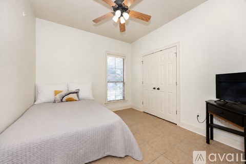 A bedroom with a bed, a ceiling fan, and a television.