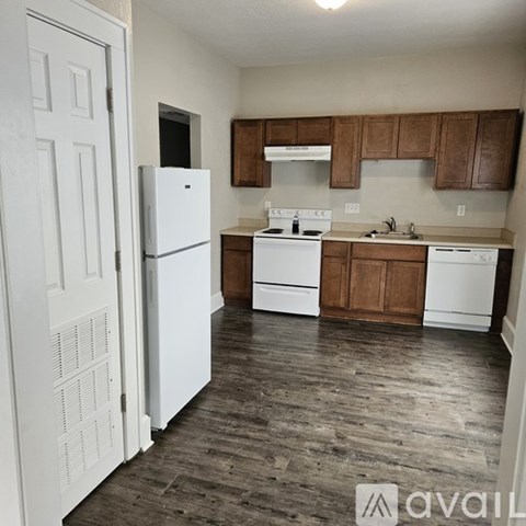 A kitchen with white appliances and wooden cabinets.