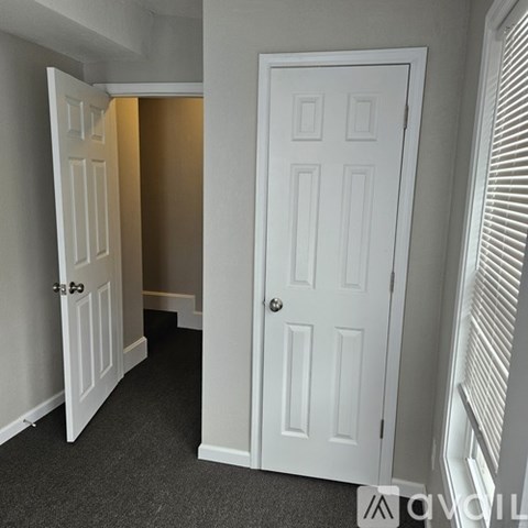 A white door is in a hallway with a carpeted floor.