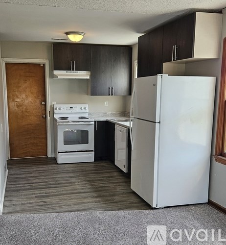 A kitchen with white appliances and dark wood cabinets.