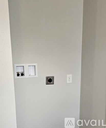 A wall with a socket, a switch and a small square hole.