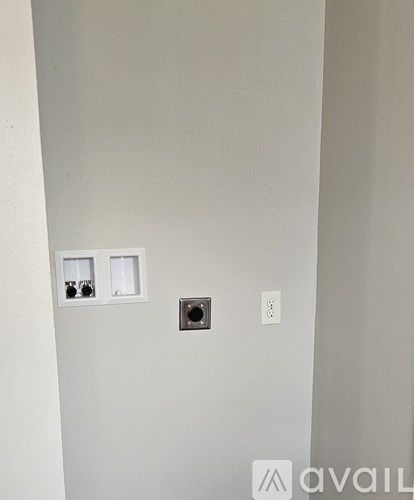 A wall with a socket, a switch and a small square hole.