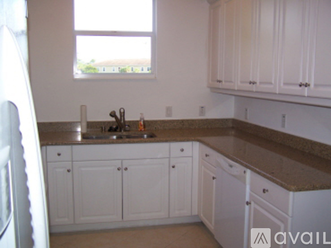 A kitchen with white cabinets and brown countertops.