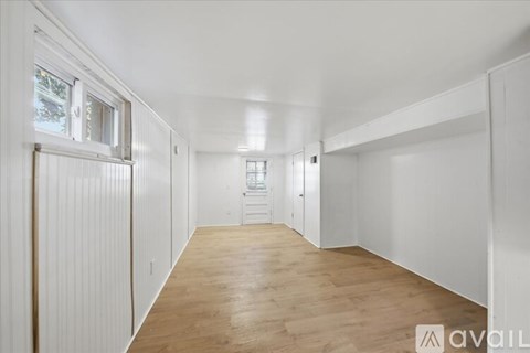 A spacious room with wooden flooring and white walls.