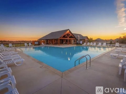 A large swimming pool with a building in the background and chairs around the pool.