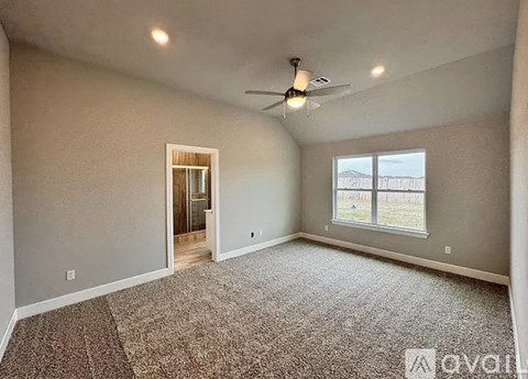 A spacious room with a ceiling fan and a rug on the floor.