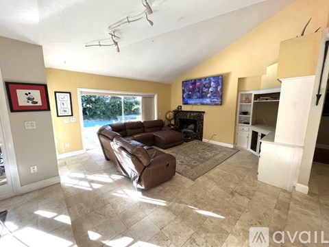 A living room with a brown leather couch and a flat screen TV mounted on the wall.