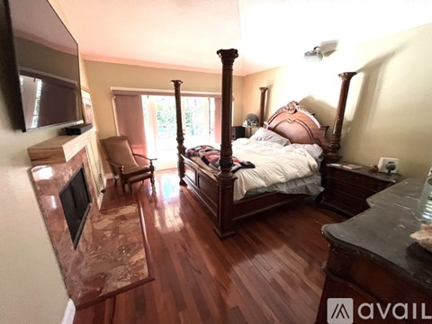 A bedroom with a four poster bed and a fireplace.