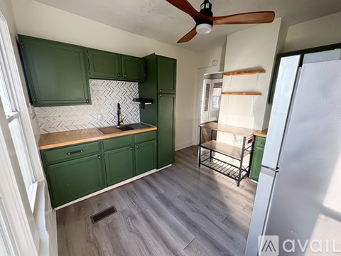 A kitchen with green cabinets and a fan on the ceiling.