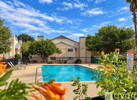 A pool surrounded by trees and a building in the background.