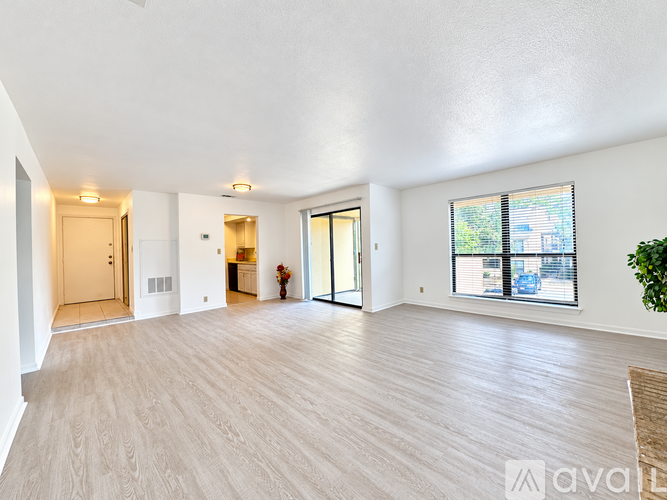 A spacious room with wooden flooring and white walls.