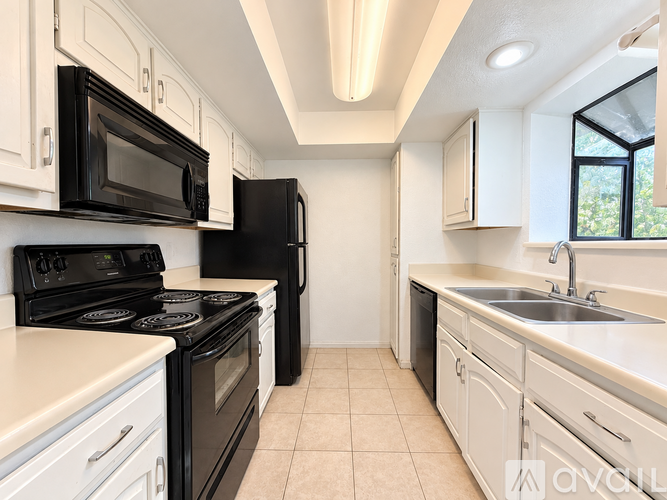 A kitchen with black appliances and white cabinets.
