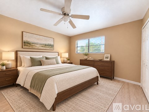 A bedroom with a large bed, a ceiling fan, and two nightstands.