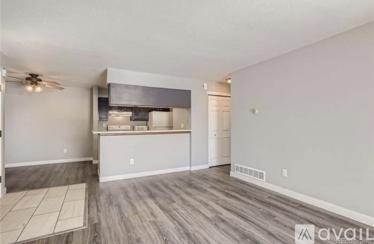 A room with a ceiling fan and a kitchenette area.