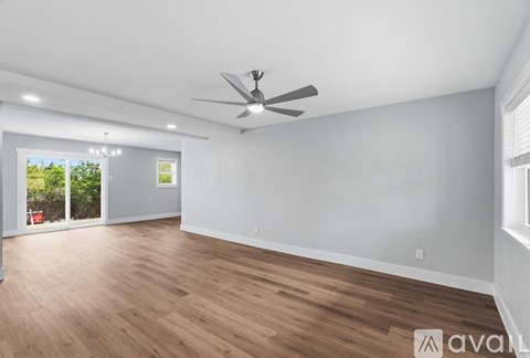 A spacious room with wooden flooring and a ceiling fan.
