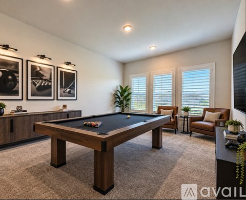 A pool table is in the middle of a room with a chair and a plant.