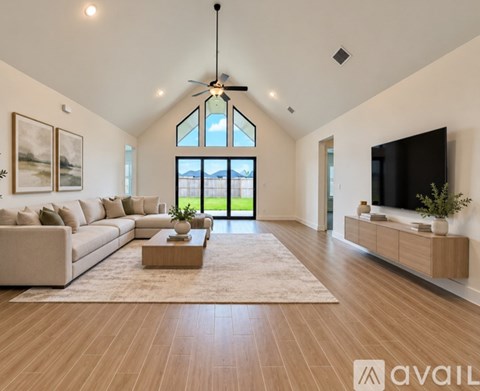 A spacious living room with a large window, a sofa, a coffee table, and a television.