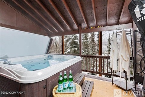 A hot tub is on a wooden deck with a bottle of Sprite on a tray.