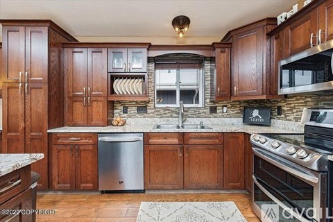 A kitchen with wooden cabinets and a stone backsplash.