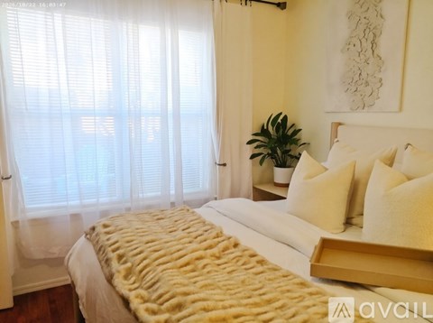 A bedroom with a bed covered in a tan furry blanket.