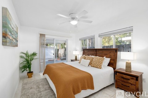 A bedroom with a bed, a ceiling fan, and a painting on the wall.