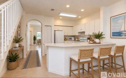 A kitchen with a white island and wooden chairs.