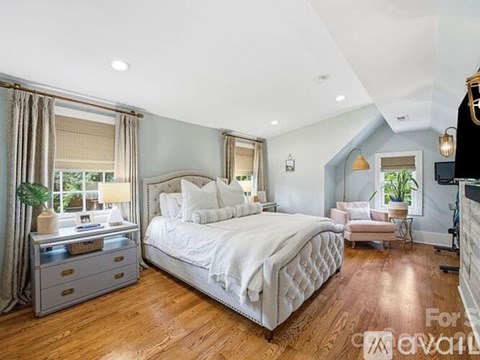 A bedroom with a large bed and a window with curtains.