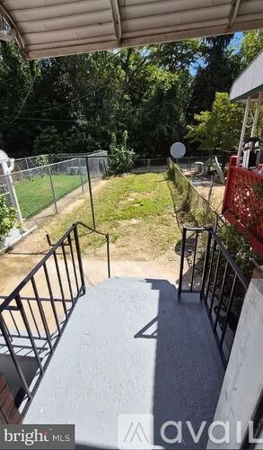 A balcony with a metal railing and a view of a yard and trees.